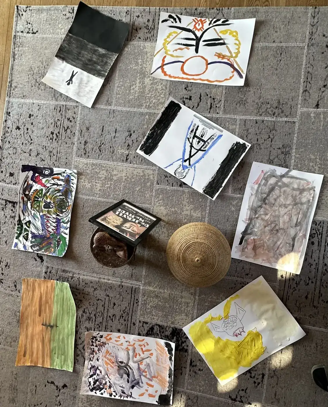 Disegni su carta disposti su un tappeto, visti dall’alto