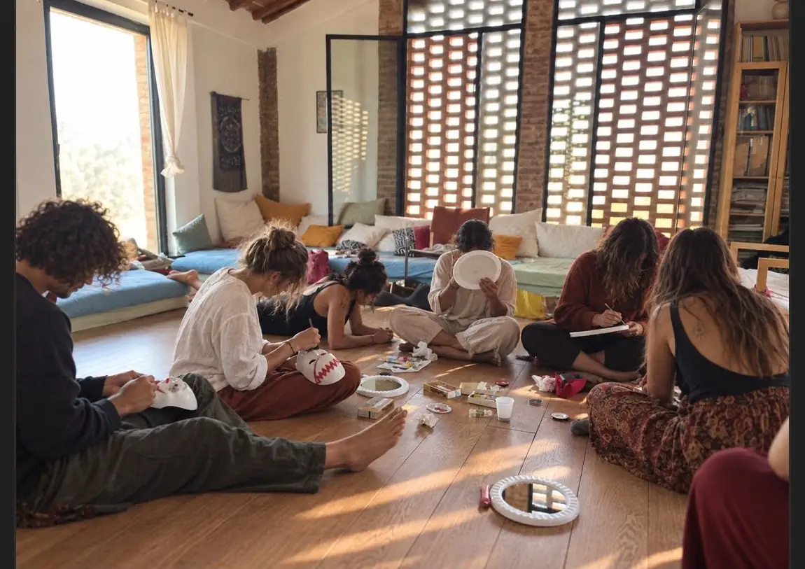 Un gruppo seduto per terra lavora con colori e fogli nel salone