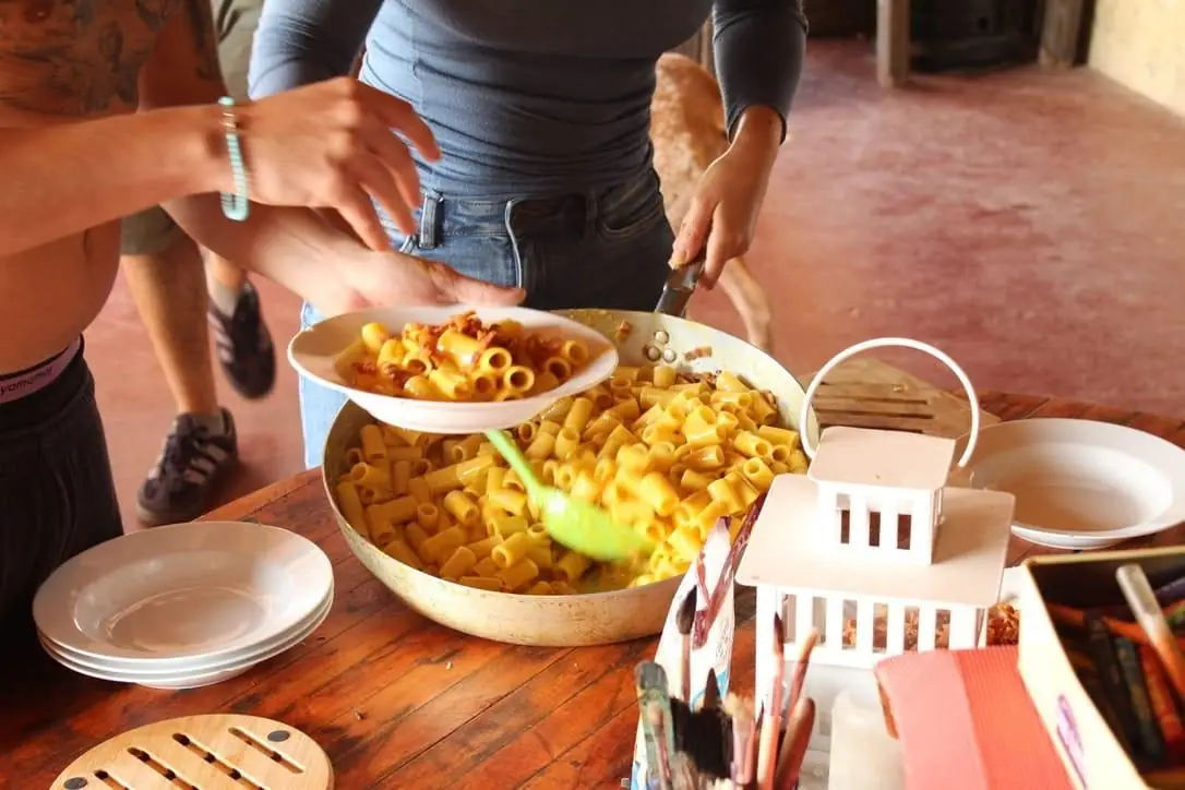 Mani che servono un piatto di pasta in una grande ciotola