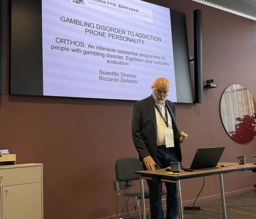 Riccardo Zerbetto presenta Progetto Orthos a un congresso, davanti a una slide sul programma residenziale e sulla valutazione degli esiti a diciotto anni