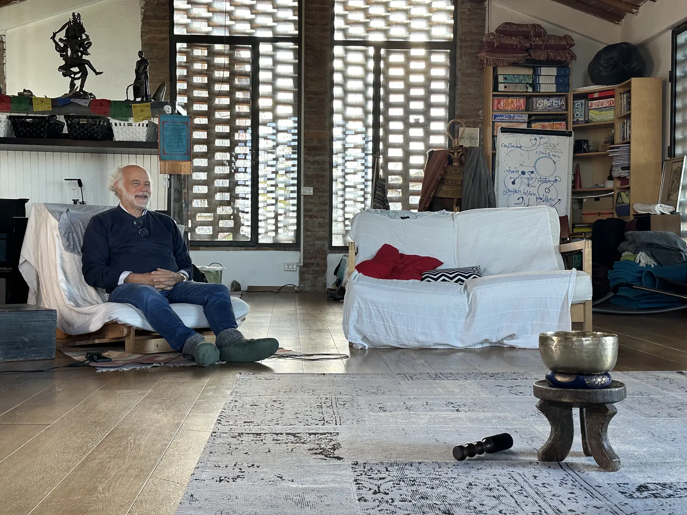 Riccardo Zerbetto ride, seduto nel salone, con una campana tibetana in primo piano